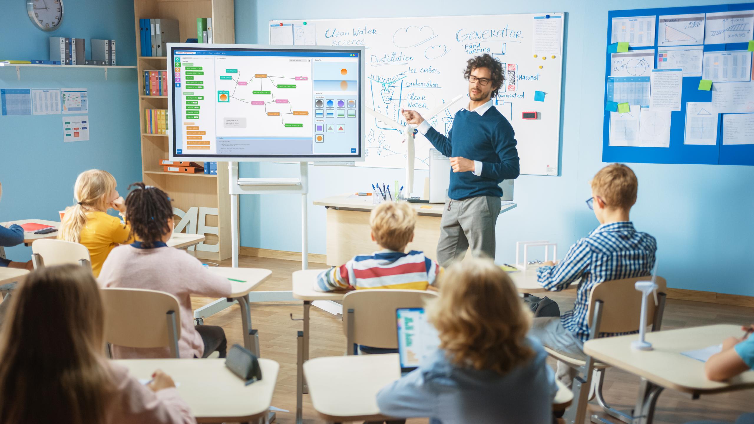 Elementary School Computer Science Teacher Uses Interactive Digital Whiteboard to Show Programming Logics to a Classroom full of Smart Diverse Children